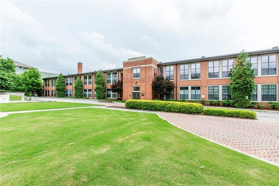 Front view of a two-story brick building with large windows and a landscaped lawn.