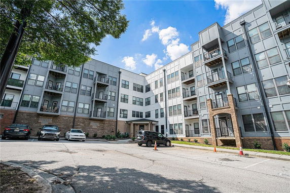 Front view of a multi-story apartment building with balconies and parking area.