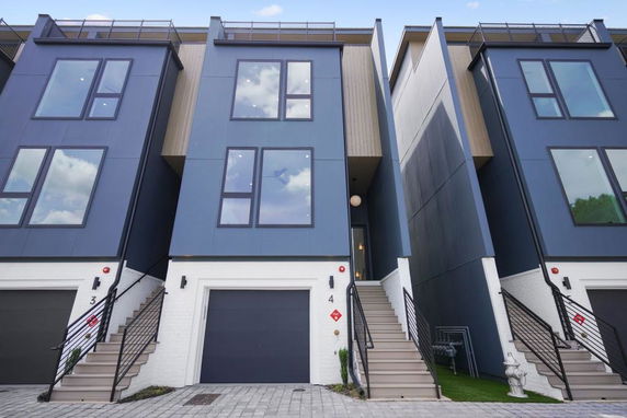 Front view of a modern multi-story townhouse with large windows and garage entrance.