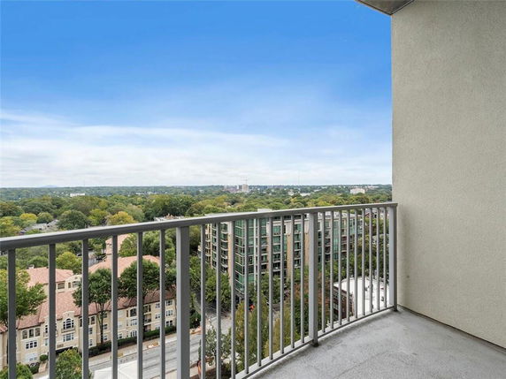 View from a high-rise balcony showing surrounding buildings and greenery.