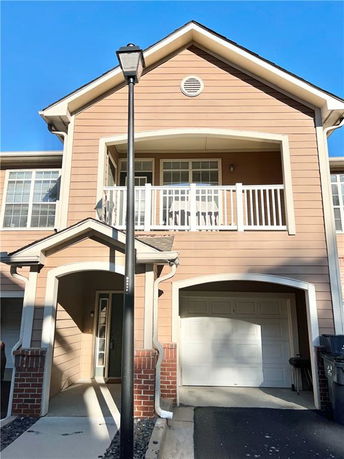 Front view of a two-story house with a balcony and a garage.