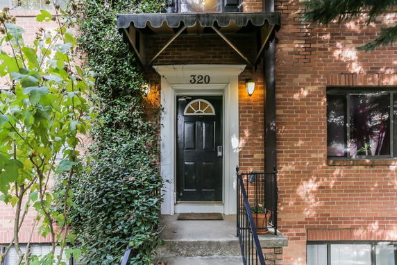 Front view of a red brick building with a black front door and an awning.