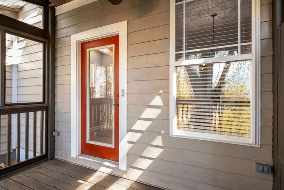 Front view of a house with a red-framed glass door and window with blinds.