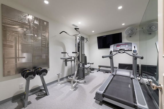 Indoor gym equipped with a treadmill, weights, and exercise machines.