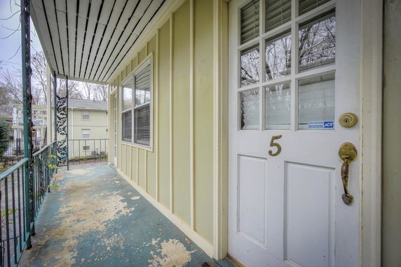 View of a building entrance with a porch and number 5 on the door.