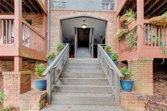 Front view of a multi-story building entrance with brick facade and stairs leading up.