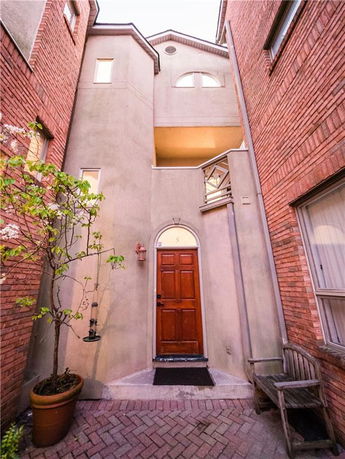 Front view of a multi-story townhouse with a wooden door and brick exterior.