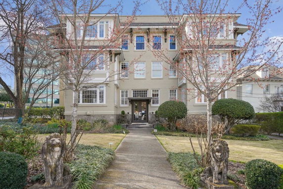 Front view of a multi-story residential building with symmetrical design and decorative stone lion statues at the entrance.