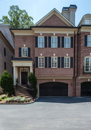 Front view of a multi-story brick house with a double garage and black shutters.