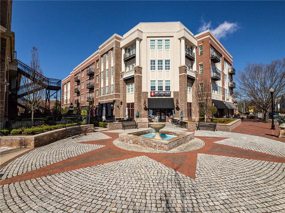 Front view of a multi-story brick building with balconies and a central open area featuring a fountain.