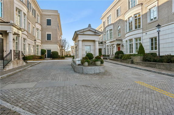 Front view of multiple three-story brick buildings with large windows and a paved courtyard.