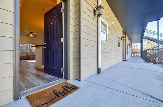 Exterior view of a building hallway with open door leading to an interior space.