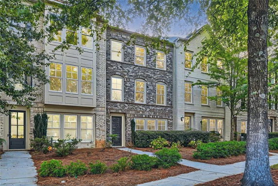 Front view of a multi-story townhouse complex with brick and siding exterior.