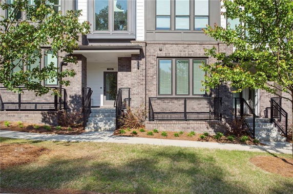 Front view of a brick townhouse with steps leading to the entrance.