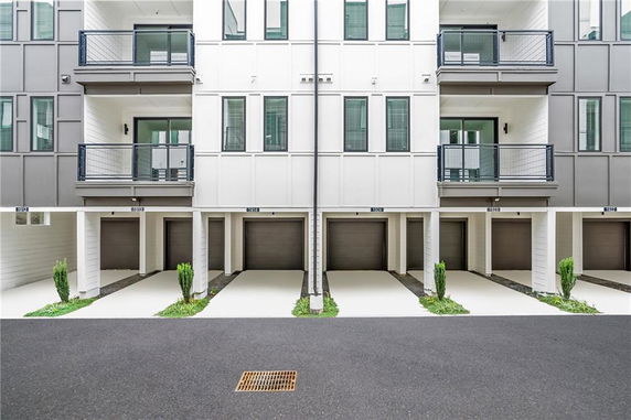 Front view of a modern multi-story building with balconies and garage entrances.