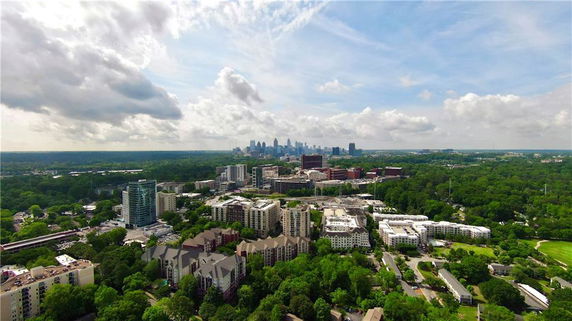 Wide-angle view of urban and green landscape with city skyline in the distance.