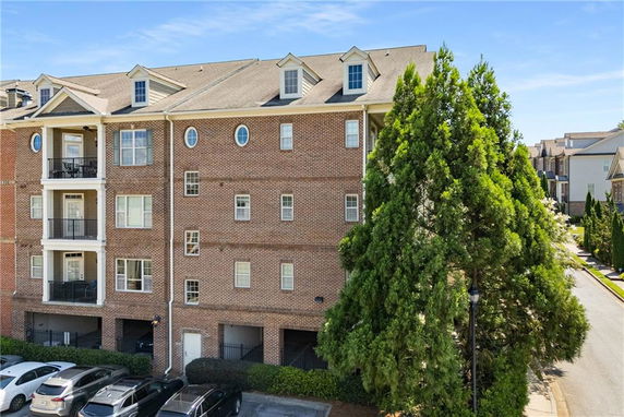Front view of a multi-story brick building with balconies and large windows.