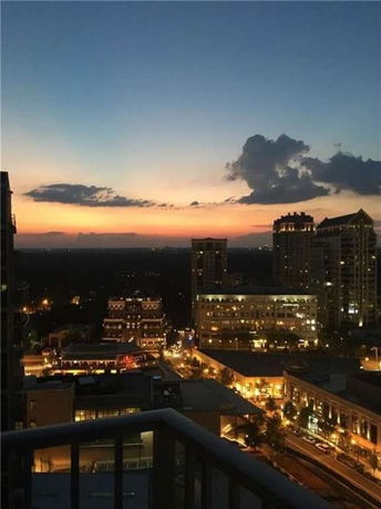 Panoramic view of city skyline at dusk with illuminated buildings and a colorful sky.