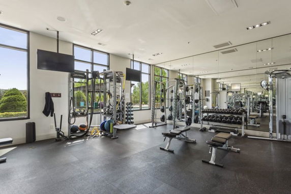 Interior view of a gym with exercise equipment and large mirrors.