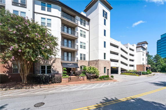 Front view of a multi-story building with balconies and parking structure.