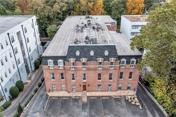 Front view of a multi-story brick building with a flat roof and several windows.
