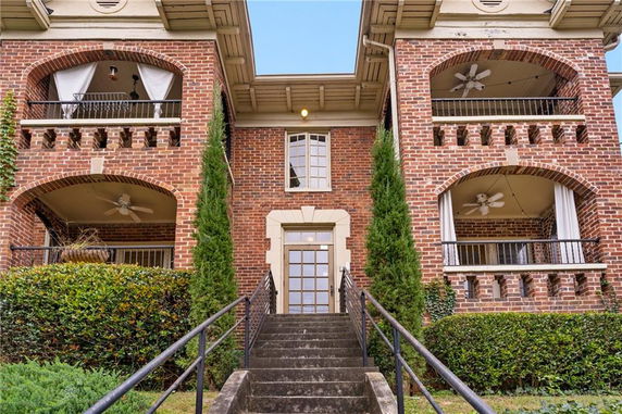 Front view of a multi-story brick building with balconies and stairs leading to the entrance.