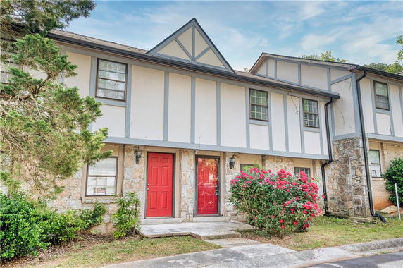 Front view of a two-story house with red doors and stone accents.