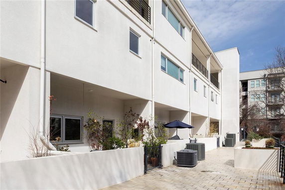 View of a multi-story building with balconies and outdoor air conditioning units.