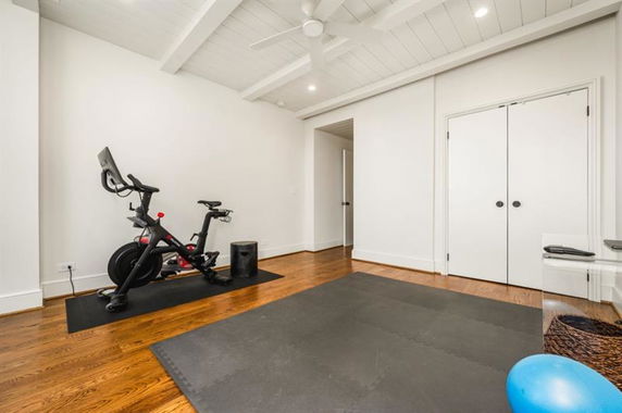 Room with exercise equipment including a stationary bike and mats.