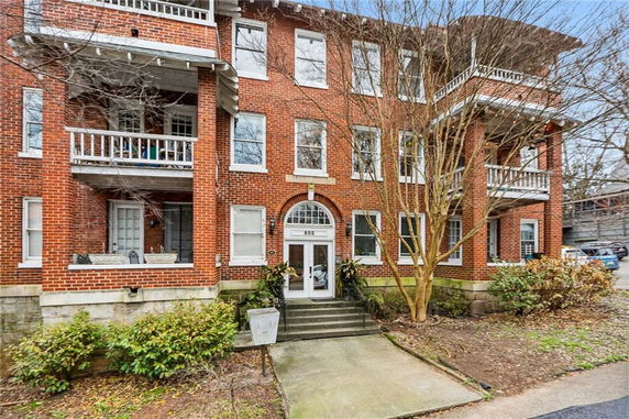 Front view of a multi-story brick apartment building with balconies.