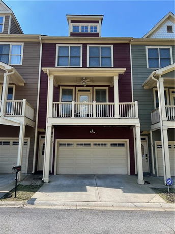 Front view of a multi-story townhouse with a garage and balcony.