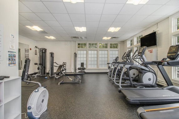Interior view of a gym with exercise equipment including treadmills and weight machines.