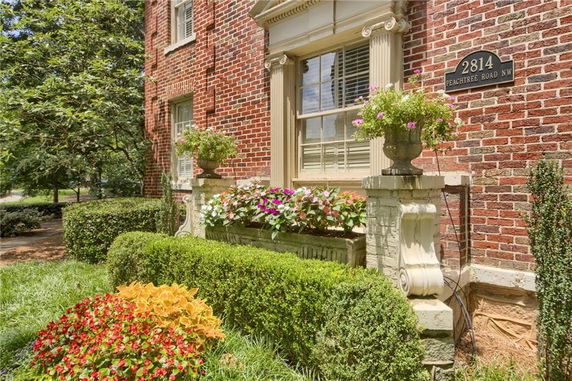 Front view of a brick building with decorative window elements and plants.