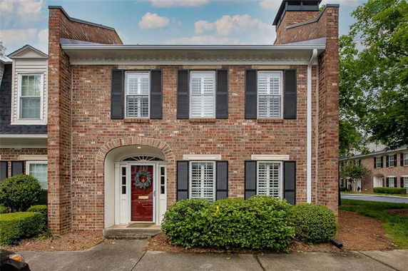 Front view of a brick two-story house with a central entryway and shuttered windows.
