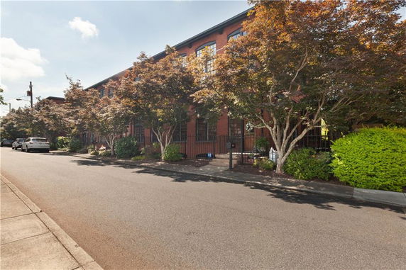 Front view of a multi-story brick building with trees lining the sidewalk.