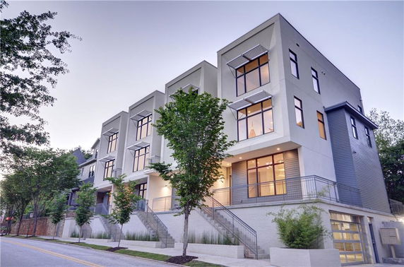 Front view of a modern multi-story townhouse with large windows and steps leading up to the entrance.