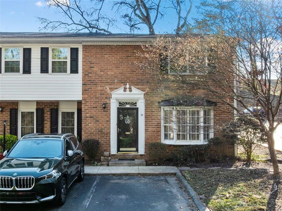 Front view of a two-story brick house with white trim and a parked car in the driveway.