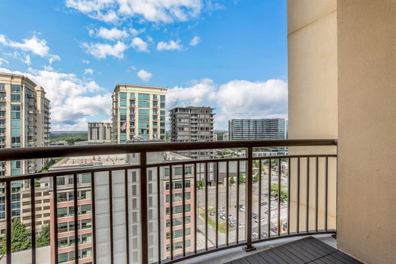 View from a balcony overlooking surrounding buildings and a clear sky.