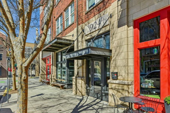 Front view of a multi-story building with red-framed windows and entry doors.