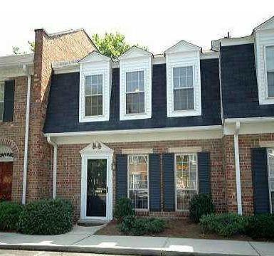 Front view of a two-story townhouse with a brick exterior and dormer windows.