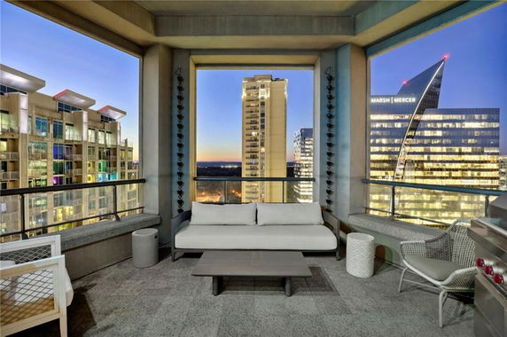 Panoramic view of cityscape from a balcony with outdoor seating area.