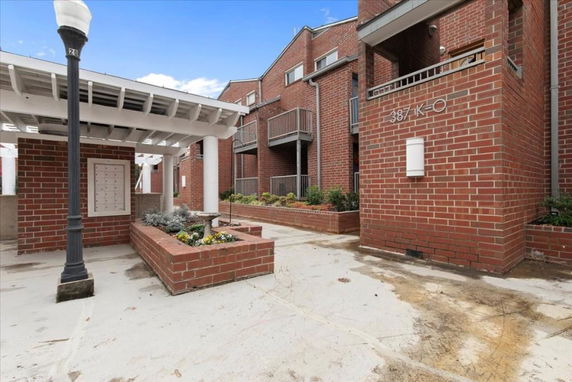 Front view of a multi-story brick building with balconies and a covered entrance area.