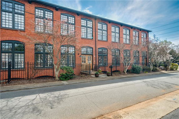 Front view of a two-story brick building with large windows and a metal fence.