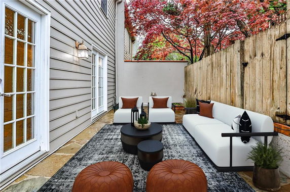 Outdoor patio area with seating and a rug next to a house.