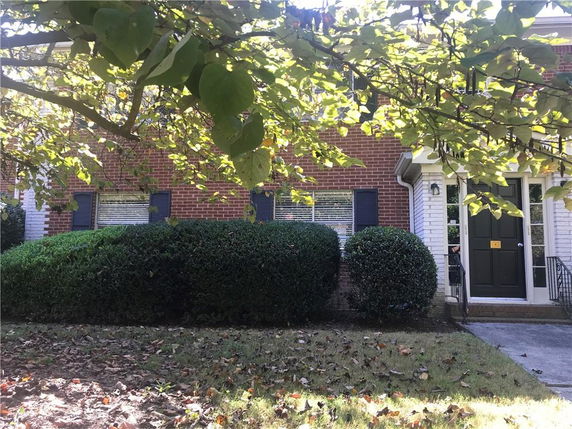 Front view of a two-story brick house with a dark door and windows with shutters.