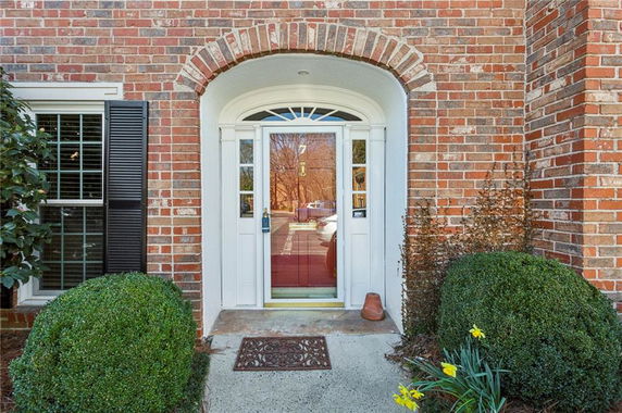 Front view of a brick house entrance with an arched doorway.