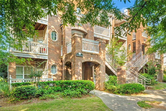 Front view of a multi-story brick apartment building with balconies and staircases.