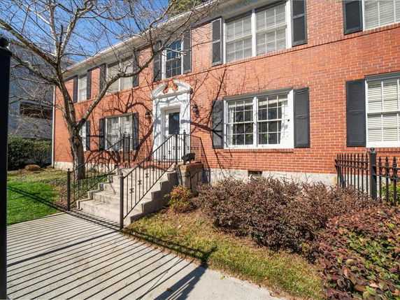 Front view of a two-story brick house with steps leading to the entrance.