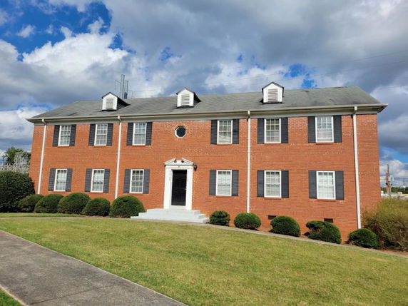Front view of a two-story brick building with white trim and black shutters.