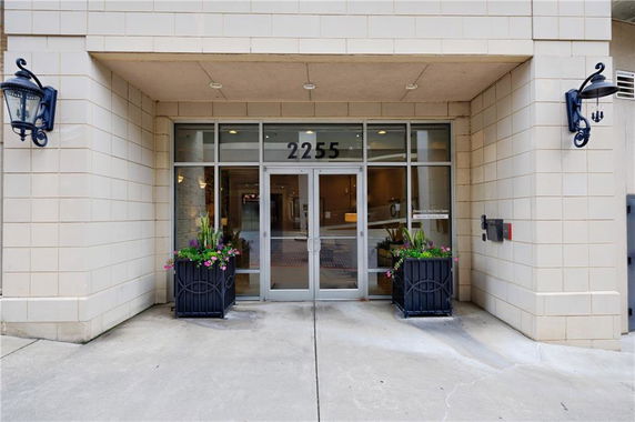 Front view of a building entrance with glass doors and planters.